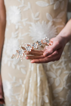 Bride holding a rose gold and crystal bridal hair comb.