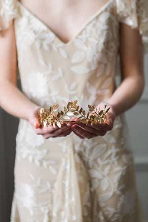 Bride holding a gold laurel leaf tiara