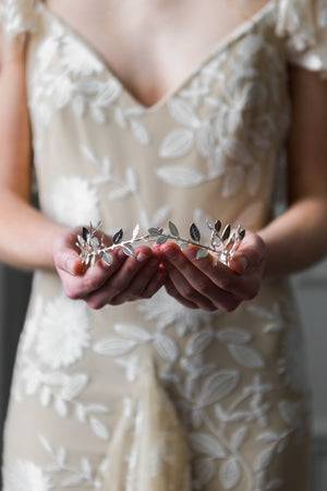 Bride holding a delicate silver leaf tiara