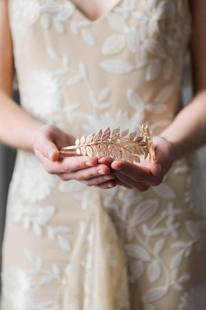 Bride holding a gold leaf headpiece