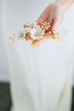 Bride holding a headpiece made of gold leaves and ivory flowers
