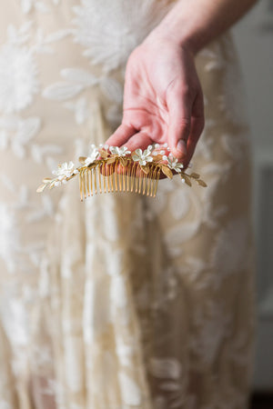 Bride holding a gold leaf and crystal bridal hair comb.