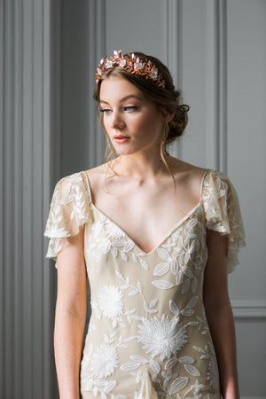 A bride wearing a rose gold laurel leaf flower crown