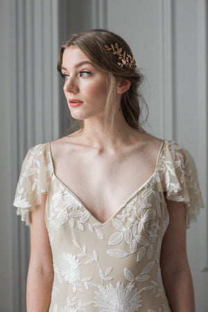 Model in a wedding dress wearing a gold leaf wrap headpiece