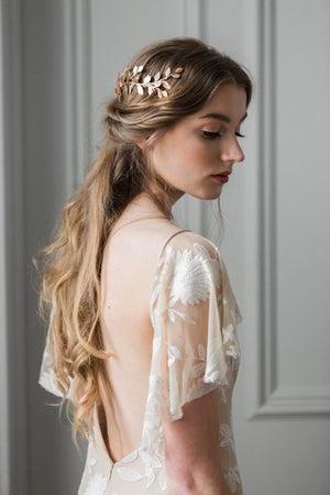 Model in a wedding dress wearing a gold leaf wrap headpiece