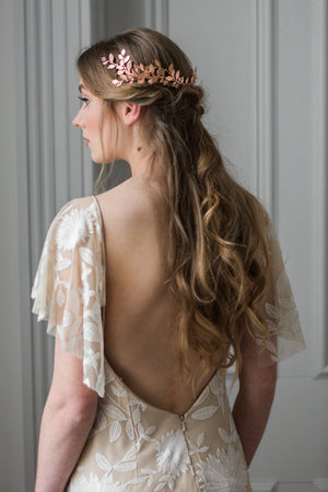 Model in a wedding dress wearing a gold leaf wrap headpiece