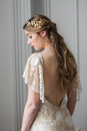 Model wearing a gold laurel leaf bridal headpiece on the back of her head