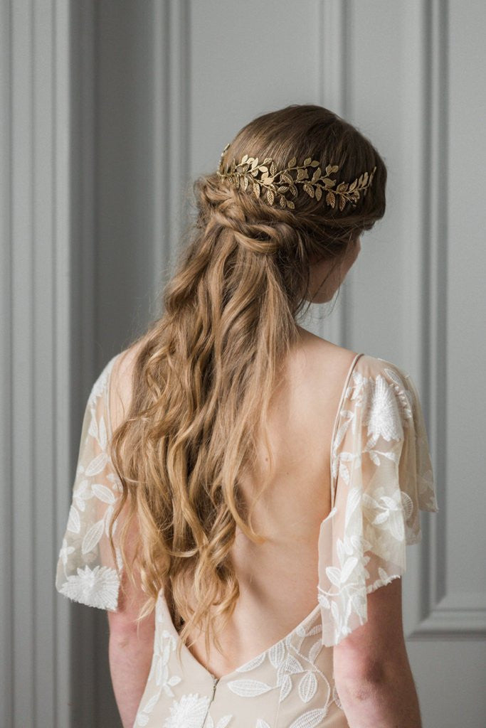 Model in a wedding dress wearing a gold leaf wrap headpiece