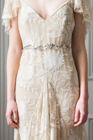 Model in a wedding dress wearing a silver leaf sash