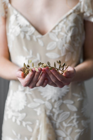 A bride holding a delicate gold leaf tiara
