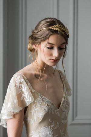 Model wearing a bridal headpiece made of gold leaves