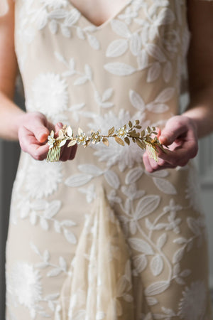 Bride holding bridal headpiece made of gold vines