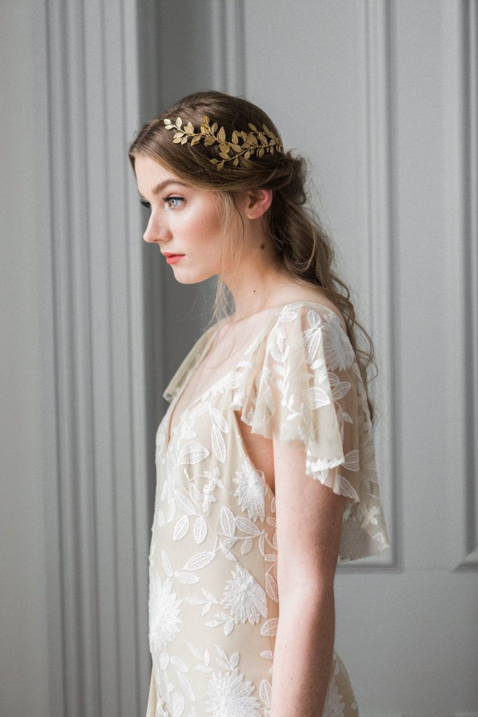 Model in a wedding dress wearing a gold leaf wrap headpiece