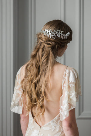 Model in wedding dress wearing a silver bridal headpiece