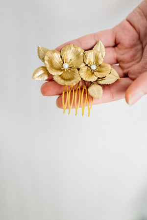 Model holding a hair comb made of gold flowers