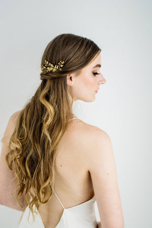Model wearing a bridal headpiece made of gold leaves and flowers