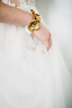 Bride wearing a bracelet made of three gold flowers