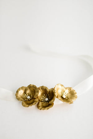 Close up of a bracelet made of three gold flowers