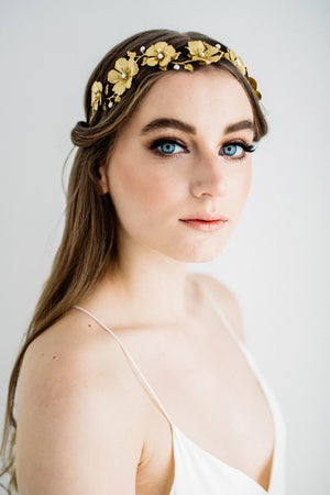 a bride wearing a headpiece made of gold leaves and flowers